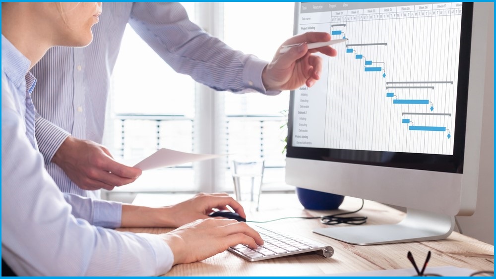 Two people looking at a project timeline on a screen